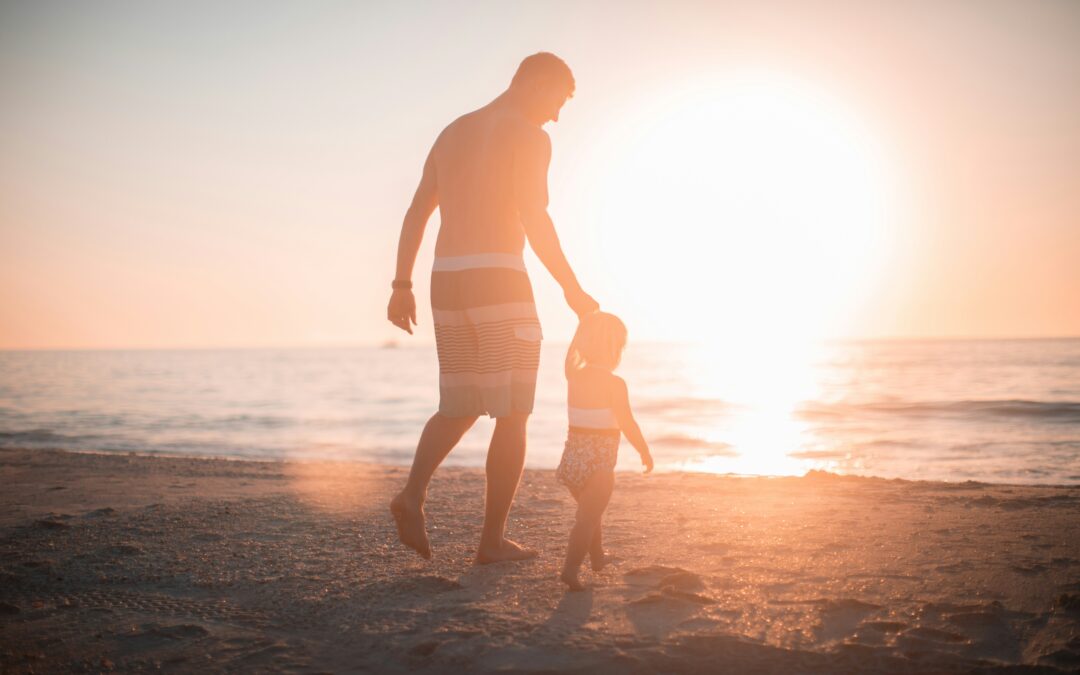 Padre e figlio, mano nella mano, al tramonto in spiaggia.